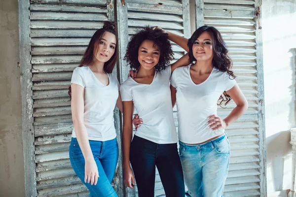 Hermosas chicas sonrientes que se divierten en camisas blancas en el fondo de la pantalla vieja. Camiseta maqueta . — Foto de Stock