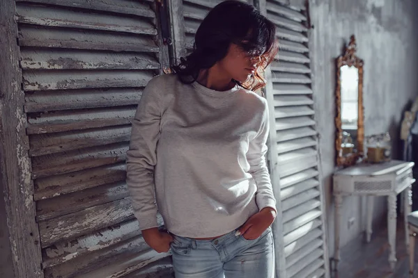 Hermosa mujer joven vestida con sudadera en blanco de pie sobre fondo de pared de madera. Mock-up . — Foto de Stock