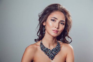 Makyaj şık kolye ve küpe gri bir arka plan üzerinde olan güzel kadın.