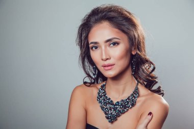 Makyaj şık kolye ve küpe gri bir arka plan üzerinde olan güzel kadın.