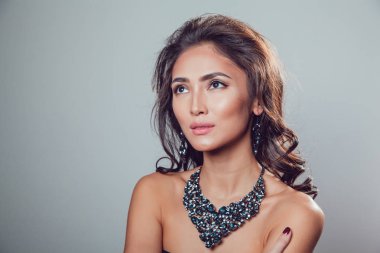 Makyaj şık kolye ve küpe gri bir arka plan üzerinde olan güzel kadın.