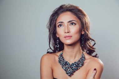 Makyaj şık kolye ve küpe gri bir arka plan üzerinde olan güzel kadın.
