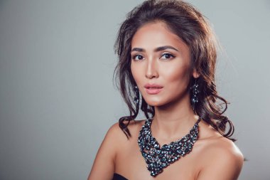 Makyaj şık kolye ve küpe gri bir arka plan üzerinde olan güzel kadın.