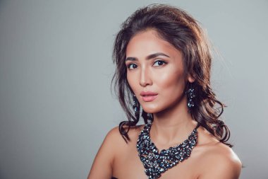 Makyaj şık kolye ve küpe gri bir arka plan üzerinde olan güzel kadın.