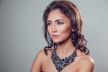 Makyaj şık kolye ve küpe gri bir arka plan üzerinde olan güzel kadın.