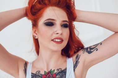 Kızıl saçlı ve bir dövme ile güzel seksi kız portresi. Kalıcı makyaj ve bukleler kadın ile.