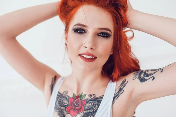 Retrato de uma linda garota sexy com cabelo vermelho e uma tatuagem. Mulher com maquiagem e cachos . — Fotografia de Stock