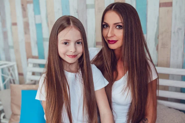 Mom and daughter with beautiful long hair and wearing the same clothes — Stock Photo, Image
