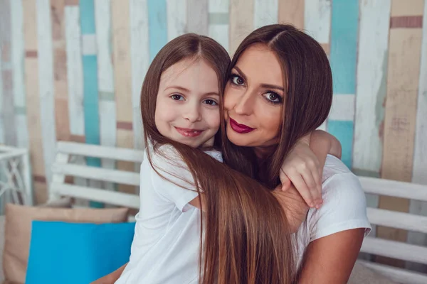 Maman et fille avec de beaux cheveux longs sont assis dans l'étreinte . — Photo