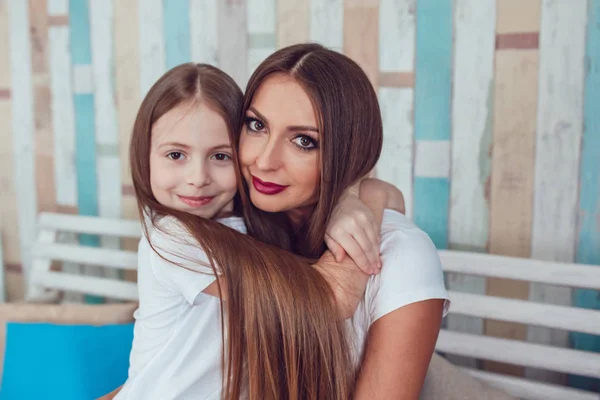 Mom and daughter with beautiful long hair are sitting in embrace. — Stock Photo, Image