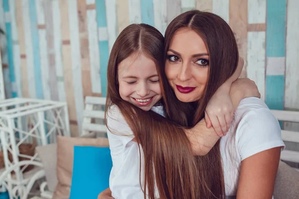 Mom and daughter with beautiful long hair are sitting in embrace. — Stock Photo, Image