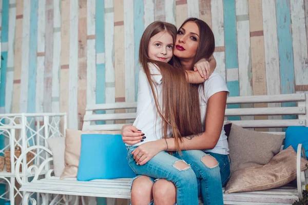 Mom and daughter with beautiful long hair are sitting in embrace. — Stock Photo, Image