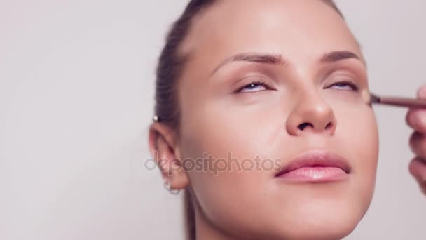 The make-up artist puts shadows on the eyelid of the model with a makeup brush. Close up. — Stock Video