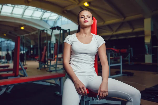 Schönes Mädchen, das in der Turnhalle sitzt und leeres weißes T-Shirt und Strumpfhosen trägt. Attrappe. — Stockfoto