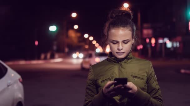 Mulheres usando telefone inteligente enquanto caminham na cidade no nigth. Pessoas urbanas estilo de vida fundo . — Vídeo de Stock