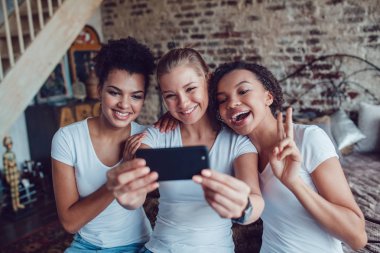 Güzel kızlar eğleniyor ve yatağın oturan selfie yapmak.