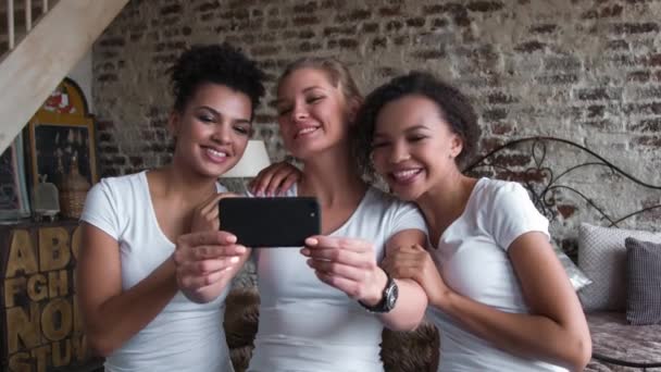Όμορφη και αστεία κορίτσια στα λευκά μπλουζάκια καθιστά selfie. Δύο Αφρο-Αμερικανοί και μία Ευρωπαϊκή κορίτσια. — Αρχείο Βίντεο