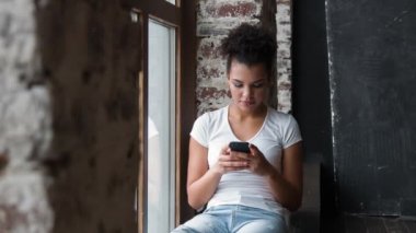 Smartphone kullanarak yapmak çekici gülümseyen Afrikalı-Amerikalı kadın.