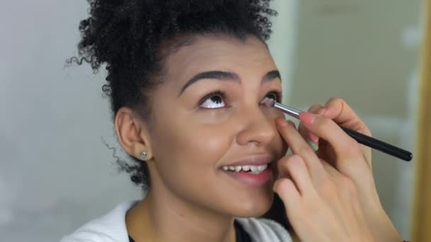 Επαγγελματία make-up artist κάνει μακιγιάζ της αφρο-αμερικανικό μοντέλο. Έννοια της ομορφιάς και μόδας. — Αρχείο Βίντεο