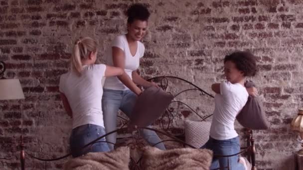 Drie aantrekkelijke meisjes vechten kussens op het bed. — Stockvideo