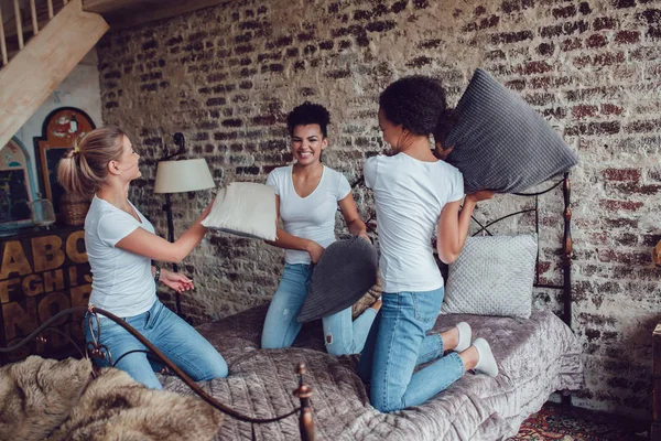 Chicas atractivas se divierten y luchan almohadas en la cama . — Foto de Stock