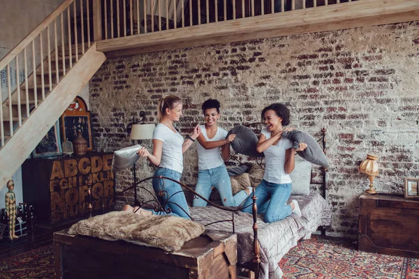 Chicas atractivas se divierten y luchan almohadas en la cama . — Foto de Stock