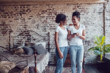İki çekici Afrikalı kızlar evde smartphone kullanın.