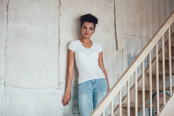 Hermosa chica africana en camiseta blanca de pie en casa . — Foto de Stock