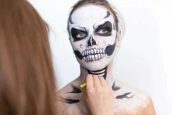 Visagist make-up het meisje halloween maken op een witte achtergrond. Halloween gezicht kunst. — Stockfoto