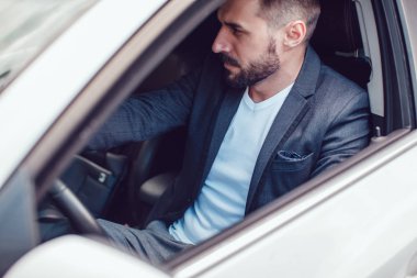 Şık adam sakallı ve güneş gözlüğü arabada oturuyor.