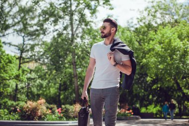 Elinde bir çanta ile sokakta şık adam sakallı ve güneş gözlüğü standları.