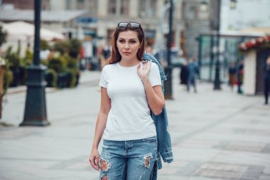 Beyaz bir T-shirt ve jeans cadde boyunca yürüme çekici kız. Mock-up.