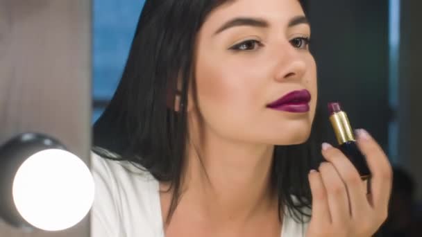 La bella mujer se pinta los labios mirándose al espejo. Hacer maquillaje labial . — Vídeo de stock