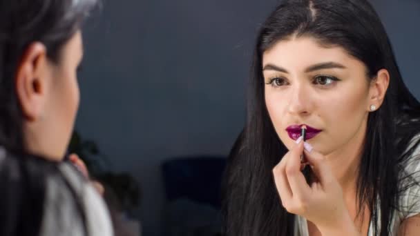 Beautiful woman is painting her lips looking in the mirror. Doing lip make-up. — Stock Video