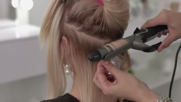 Cabeleireiro faz um cachos para uma menina, usando o estilo de cabelo. Cabeleireiro no trabalho . — Vídeo de Stock