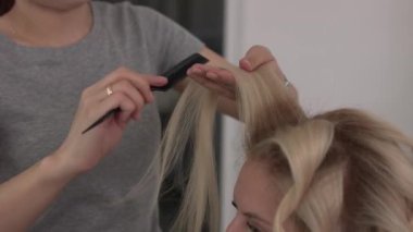 Saç stilisti bir kıvırcık saç şekillendirme kullanan bir kız için yapar. Kuaför iş başında.