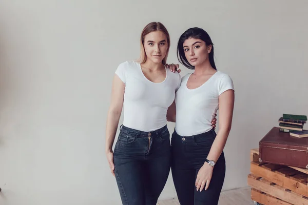 Zwei schöne Frauen in weißen T-Shirts im Studio. Attrappe. — Stockfoto