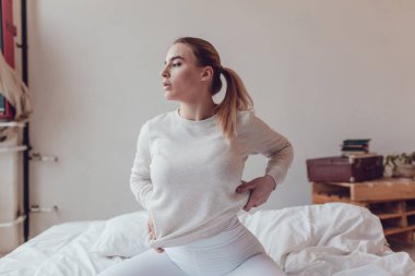 Gri sweatshirt seksi sarışın kadın yatakta oturur. Mock-up.