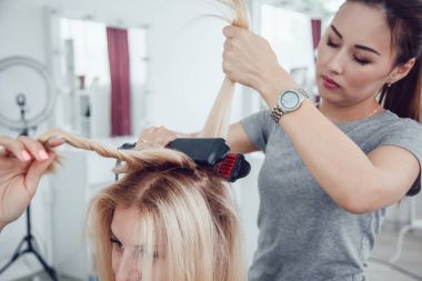 Kuaför stilist styling saç şekillendirme kullanan kız için yapar. Saç oluklu.