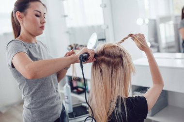 Kuaför stilist styling saç şekillendirme kullanan kız için yapar. Saç oluklu.