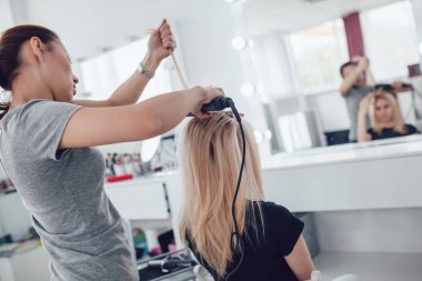 Kuaför stilist styling saç şekillendirme kullanan kız için yapar. Saç oluklu.