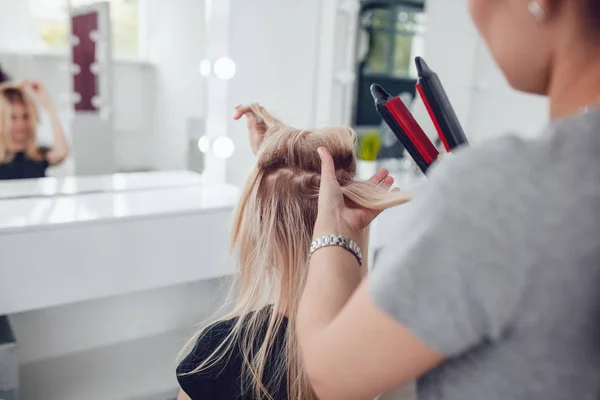 Перукар-стиліст робить стиль дівчині, використовуючи зачіску. Гофровані на волоссі . — стокове фото