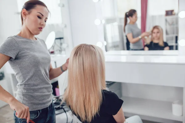 Peluquero por peines cabello chica cabello en estudio de belleza . — Foto de Stock