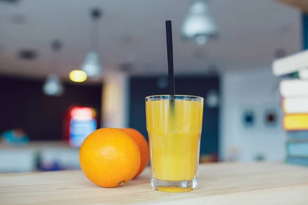 Vaso de zumo de naranja con frutas y pajitas de cóctel sobre una mesa . — Foto de Stock