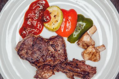 Izgara sebzeli biftek beyaz tabakta.