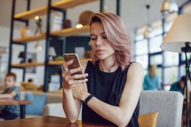 Bir kafede Smartphone kullanarak çekici kadın.