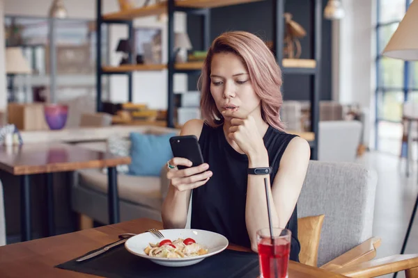 Smartphone kullanarak ve bir kafede yemek çekici kadın.