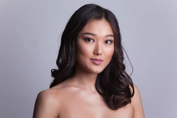 Portret van een mooie Aziatische vrouw met naakte schouders. — Stockfoto