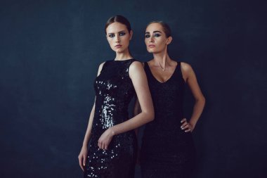 Siyah bir arka plan üzerinde poz iki güzel kadın siyah gece moda elbise.