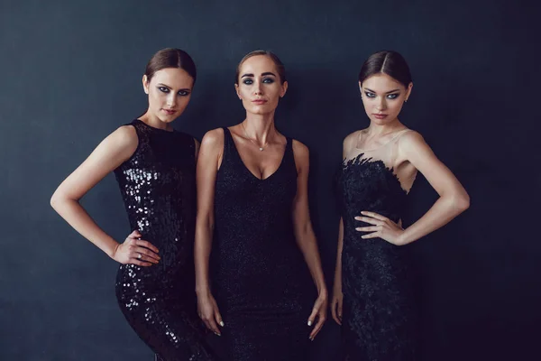 Привабливі дівчата в чорних коктейльних сукнях на темному тлі . — стокове фото